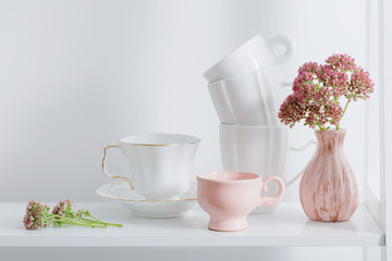 Clean dishes and flowers on wooden shelf