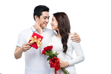 Asian man makes present to his lovely sweetheart. Young man giving a gift. Cheerful young couple man and woman at home offering to each other gifts for lover's valentine day