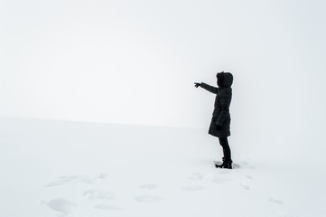 Woman in snow pointing her finger towards blank space