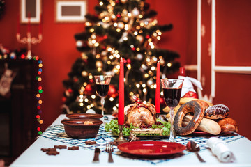 Christmas dinner by candlelight, table setting. Thanksgiving table with baked turkey in a decorated room with a Christmas tree.