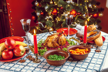 Fototapeta na wymiar Christmas dinner by candlelight, table setting. Thanksgiving table with baked turkey in a decorated room with a Christmas tree.