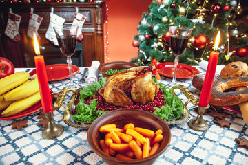 Christmas dinner by candlelight, table setting. Thanksgiving table with baked turkey in a decorated room with a Christmas tree.