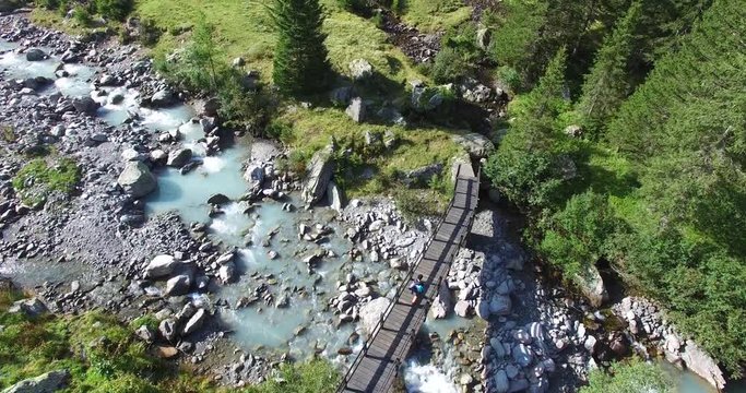 Escursionista attraversa ponte di legno su torrente di montagna - Vista aerea