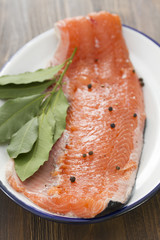 fresh salmon on white dish on wooden background