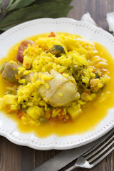 rice with seafood and chicken on white plate on wooden background