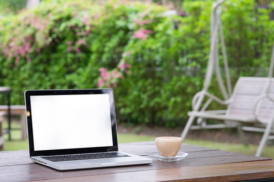 Laptop and cup of coffee in garden.