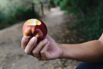 young man eating a red apple outdoors