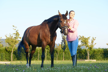 Beautiful young woman with her bay horse