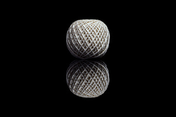 Side view of white ball of string on black background