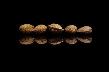 Five shelled almonds isolated on black reflective background