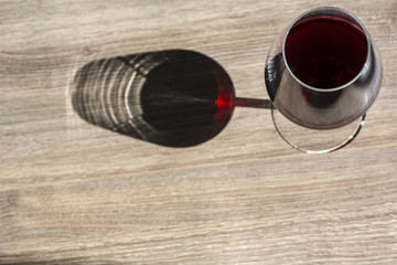 Glass of red wine on the brown wooden background with shadow