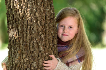 Unimaginably beautiful blond girl playing in the park hiding beh