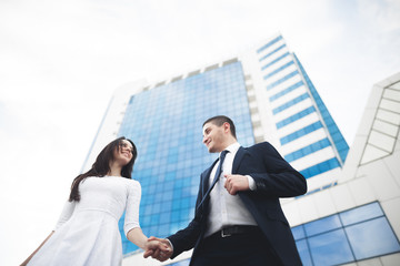 Elegant beautiful couple posing near modern glass building