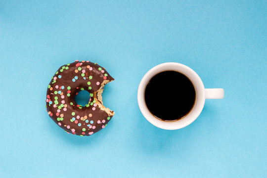 Chocolate donuts with coffee on the blue background.