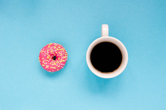 Pink donut with cup of coffee on the blue background.