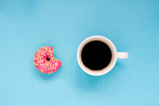 Pink donut with cup of coffee on the blue background.