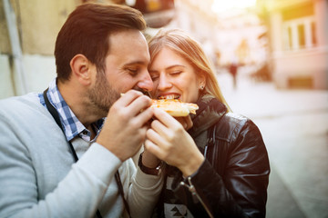 Happy couple eating pizza outdoors