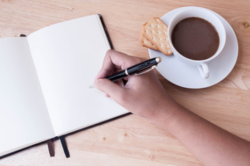 Writing in blank book on wooden table