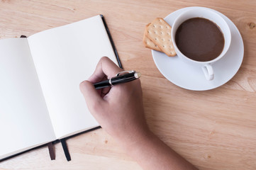 Writing in blank book on wooden table