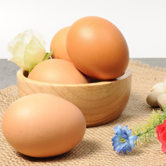 Fresh eggs on mat in wooden bowl