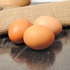 Fresh eggs on mat in wooden bowl