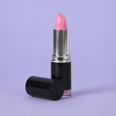 A pink lipstick on a pastel purple background