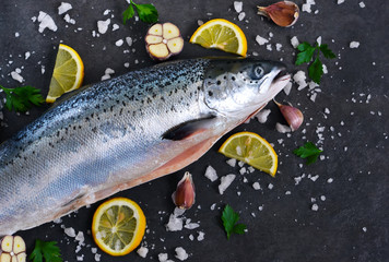 Fototapeta na wymiar Fresh raw salmon with salt and lemon on a black background. 
