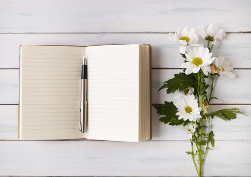 An open writers notebook with flowers on a white desktop background
