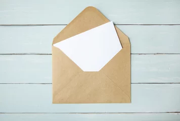 Foto op Plexiglas An open brown envelope with letter on a blue wooden desk top background © beckystarsmore