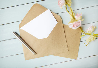 An open brown envelope with letter and writing pen on a blue wooden background