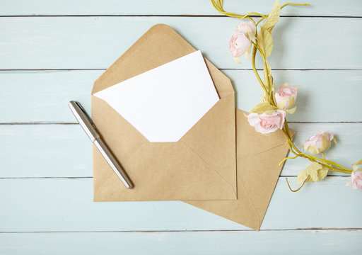An open brown envelope with letter and writing pen on a blue wooden desktop background