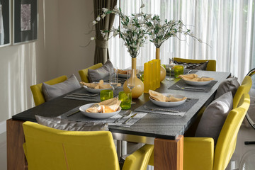 dining table and comfortable yellow chairs in modern home with elegant table setting