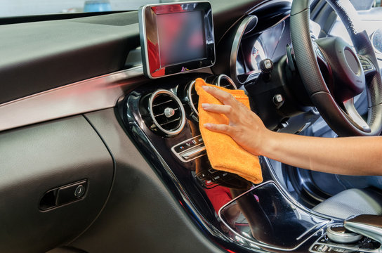 Hand with microfiber cloth cleaning interior car