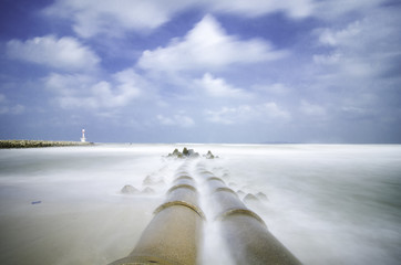 concrete drain pipeline at coastline. soft white wave hitting th