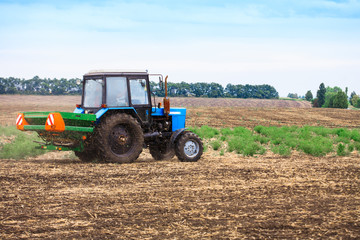 Obraz premium Rural landscape with old tractor in a field sow seed.
