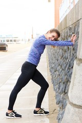 Female athlete in stretch on sidewalk