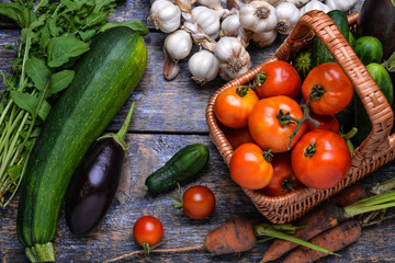 Harvest Vegetables: tomatoes, cucumbers, zucchini, eggplant, onion, garlic, arugula on the wooden background
