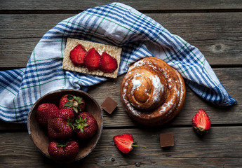 delicious breakfast with strawberries and sweet bun on wooden background. Fruit, food, chocolate