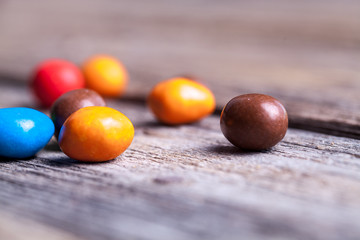 colorful candy in a wooden plate. sweets, icing, nuts