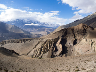 Snow mountain peak behind cloud at distance and the sand stone mountain valley as foreground, Annapurna Conservation Area, Nepal