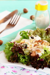 Fresh salad leaves with yogurt and hazelnuts on a plate. Diet salad recipe. Wooden background. Closeup