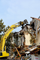 Abrissbagger mit drehbarem Greifer beim Abriss eines Wohnhauses