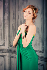 Obraz premium Woman in green evening gown stands in the fashion studio looking on us