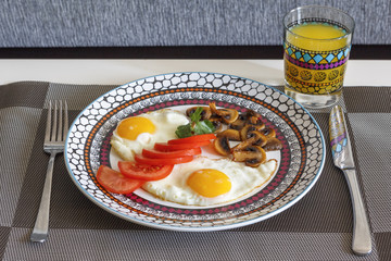 Breakfast. Fried eggs with vegetables and orange juice.