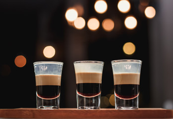 Three layered shots on a bar counter and bokeh background.