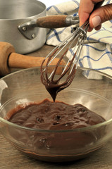 Personne tenant un fouet de cuisine avec dessus d'un saladier de crème au chocolat 