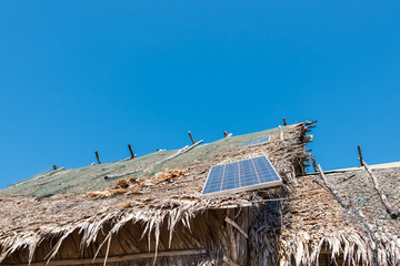 Solar panel on a roof of straw dry and the cloudless blue sky