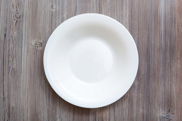 above view of white deep plate on gray brown table