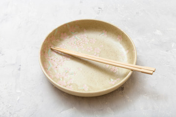 yellow plate with chopsticks on gray concrete