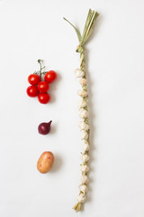 Knitted garlic, onion,  twig red tomatoes and potatoes on white